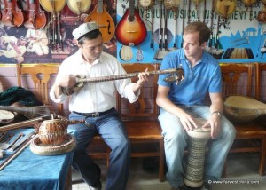 A Uyghur man teaching Josh to play a Uyghur instrument