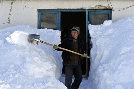 Heavy Xinjiang Snowfall A man shovels a large wall of snow