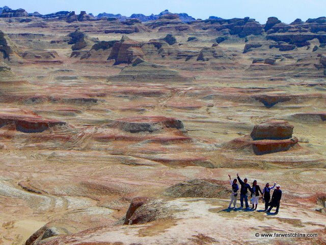 A group of people dwarfed by the Ghost City Rock Formations