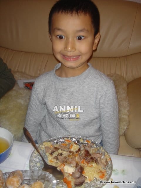 A young boy excited about his Uyghur polo plate