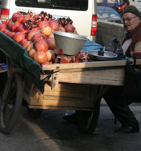 A man sells pomegranates off a street cart