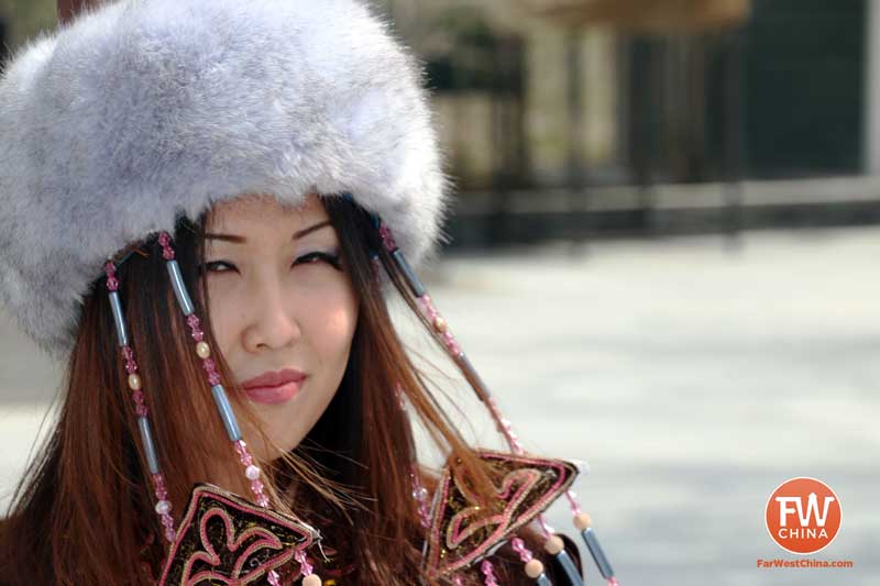 A Kazakh woman in traditional clothes smiles for the camera