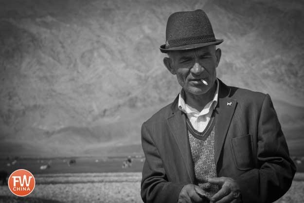 A Tajik man smoking on the grasslands in Tashkorgan, Xinjiang