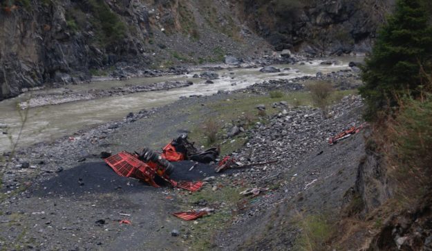 A crashed truck sits at the bottom of the valley